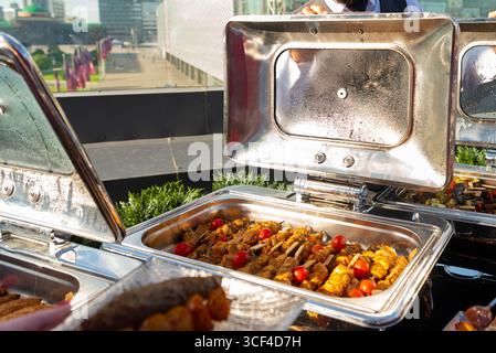 Un vivace buffet all'aperto con kebab alla griglia e pomodori ciliegini. la scena cattura una giornata di sole, perfetta per riunioni o eventi di catering Foto Stock