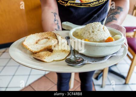 Coral Gables Miami Florida, Bagel Emporium & Grille, caffetteria ristorante, cucina ebraica, interno, cameriera ispanica che tiene in mano un vassoio che serve zuppe e palle azotate Foto Stock
