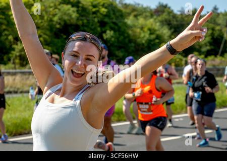 Carly McNeil, runner no 5669, salta alla telecamera mentre gareggia nella Scottish Half Marathon del 2025 in Scozia. Foto Stock