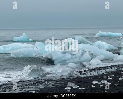 La famosa spiaggia di sabbia nera Diamond Beach in Islanda è conosciuta per gli iceberg che galleggiano nell'oceano dalla laguna del ghiacciaio Jokusarlon Foto Stock