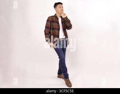 uomo premuroso che si rifà a un outfit casual su uno sfondo minimalista Foto Stock