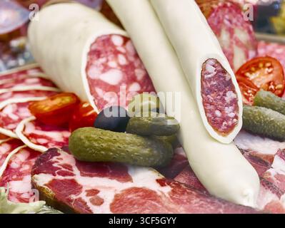 Delizioso assortimento di affettati assortiti, formaggi e verdure fresche su un piatto rustico di legno durante una riunione estiva Foto Stock
