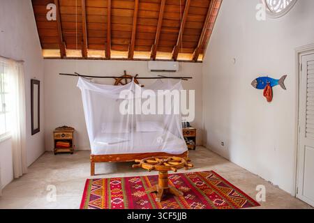 Islas del Rosario, Cartagena, Colombia - 20 agosto 2025 - Un'accogliente camera da letto con letto a baldacchino, arredamento rustico e colori vivaci creano un'atmosfera serena. Foto Stock