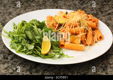 Primo piano di pasta rigatoni preparata con zucchine e rucola Foto Stock