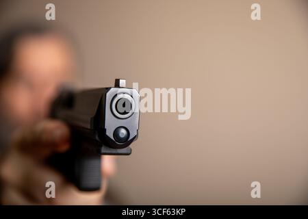 Un uomo ha in mano una pistola e la sta puntando alla telecamera Foto Stock