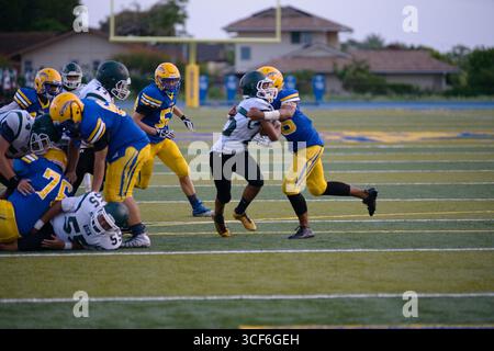 Il running back delle scuole superiori combatte per ogni yard mentre un feroce difensore cerca di portarlo giù nel drive fino alla end zone. Foto Stock