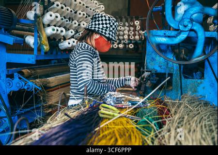 la tessitrice vietnamita lavora su un telaio in un laboratorio in una fabbrica che produce tappeti di canne intrecciati tradizionali in Vietnam in Asia Foto Stock
