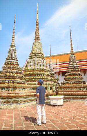 Visitatore che ammira il gruppo di Pagodas a Wat Pho o Tempio del Buddha sdraiato, Bangkok, Thailandia Foto Stock