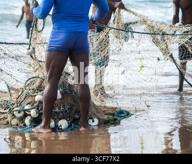 Mezzo corpo di pescatori non identificati che raccolgono la rete da pesca dopo la cattura del pesce. Pesce, pesca come hobby. Brasile Foto Stock