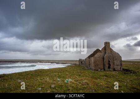 Rovinato croft dal mare sull'isola di Lewis sotto le nuvole di tempesta Foto Stock