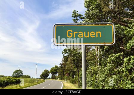 Cartello con il nome di un luogo divertente su una strada di campagna, iscrizione Grauen, cartello verde con la scritta gialla, Neuenkirchen, Lueneburg Heath, Germania Foto Stock