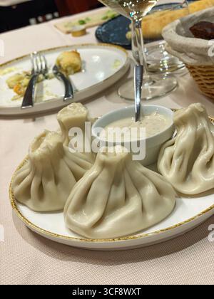 Gnocchi tradizionali di khinkali georgiani poggiati su un piatto di ceramica, accompagnati da salsa, serviti all'interno di un ristorante rustico a Silvi, Abruzzo Foto Stock