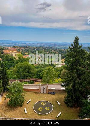 Vista panoramica della campagna toscana da Montepulciano, in Italia, con un tranquillo laghetto, vegetazione verdeggiante e uno scorcio dell'architec della città Foto Stock