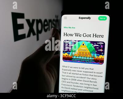 Stoccarda, Germania - 20-08-2025: Persona che possiede uno smartphone con pagina Web della società di gestione delle spese Expensify Inc. Sullo schermo davanti al logo. Foto Stock