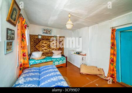 Una stanza in una casa rurale fatiscente. Pareti verdastre, mobili antichi, stoffa d'olio sul tavolo. Tappeto e vecchie foto sul muro. Foto Stock