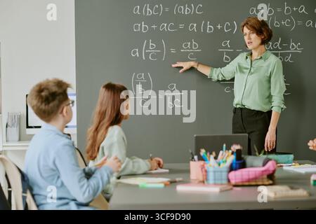 Donna caucasica di mezza età che insegna matematica agli adolescenti in classe Foto Stock