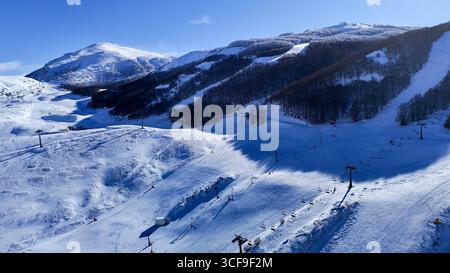 Uno splendido paesaggio invernale con skilift su una pista innevata di montagna. La neve incontaminata, le piste da sci e le ombre delle seggiovie creano un'atmosfera da brivido Foto Stock