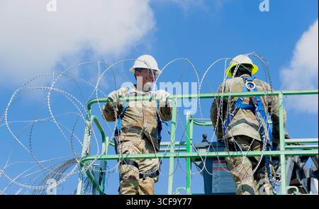 Brownsville, Stati Uniti. 12 agosto 2025. Le guardie nazionali del Texas, sotto la Joint Task Force-Southern Border, installano filo a fisarmonica lungo il muro di confine meridionale con il Messico, 12 agosto 2025 vicino a Brownsville, Texas. I soldati sono stati inviati al confine dal presidente Trump a sostegno dell'operazione Lone Star. Credito: SSgt. Derek Gutierrez/US Air Force Photo/Alamy Live News Foto Stock