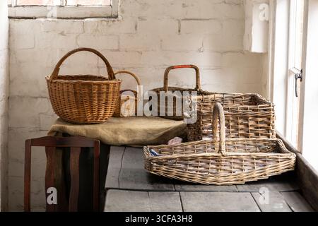 Cesti rustici in vimini su un tavolo di legno in un'accogliente sala illuminata dal sole Foto Stock