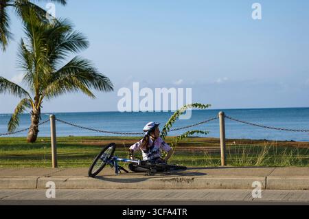 Stanca ciclista che riposa sul marciapiede durante l'Honolulu Century Ride del 2005, Hawaii Kai, Oahu, Hawaii, USA Foto Stock