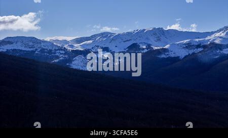Maestose montagne innevate sotto un cielo azzurro limpido all'alba nella serena natura selvaggia Foto Stock