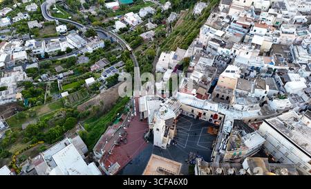Una vista mozzafiato cattura l'intricata disposizione di una comunità collinare, mostrando edifici colorati e strade tortuose mentre il sole tramonta, gettando un wa Foto Stock