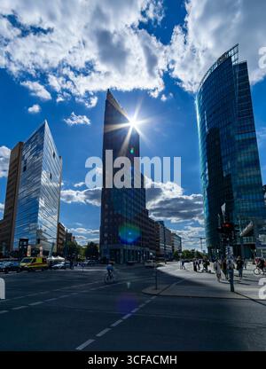 Grattacieli di Potsdamer Platz a Berlino con stella del sole sulle torri di vetro, vita di strada e atmosfera estiva in vista verticale. Foto Stock