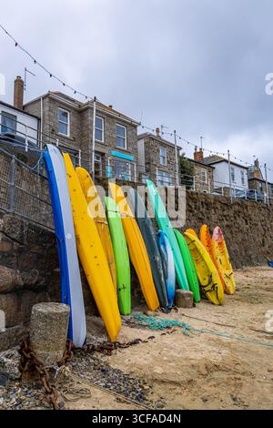 La bassa marea al porto di Mousehole in Cornovaglia, Regno Unito, rivela barche da pesca ormeggiate su fondali marini esposti, ideali per viaggi, pesca, stile di vita costiero, e. Foto Stock