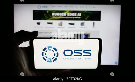 In questa immagine, una persona ha in mano un cellulare con il logo della società statunitense One Stop Systems Inc. (OSS) sullo schermo davanti alla pagina Web. Foto Stock