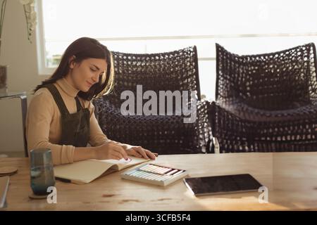 Artista femminile che disegna forme circolari in un bozzetto in casa con matite colorate, spazio copia Foto Stock