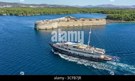 Šibenik, Croazia, Mare Adriatico: Elegante yacht a motore/mini crociera/piccola nave CASABLANCA in navigazione attraverso lo stretto Canale di Sant'Antonio fino a Sibenik Foto Stock
