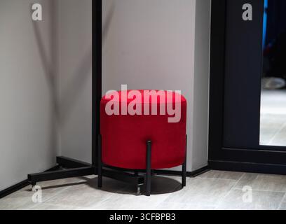Moderno pouf rosso nell'angolo del corridoio per sedersi e arredare Foto Stock