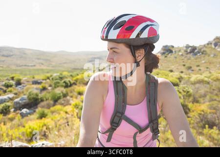 Ciclista donna in pausa su un sentiero in collina con zaino idratante e casco da bicicletta, spazio fotocopie Foto Stock