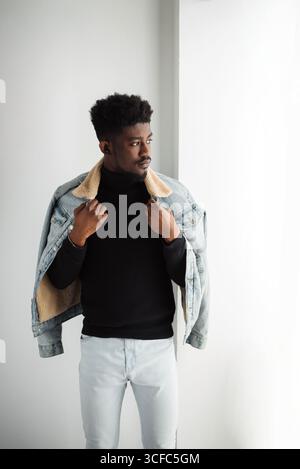 Uomo nero concentrato che indossa abiti eleganti guardando la finestra isolato su sfondo bianco studio ritratto. Concetto di stile di vita della gente Foto Stock
