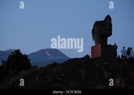 Nell'agosto del 2025 l'Etna entrò in una fase effusiva alimentata da bocche tra bocca nuova e il cratere sudorientale a 2.980–3.200 m s.l.m., inviando freschi corsi di lava lungo la base del cratere sudorientale e sui fianchi sudovest/occidentali superiori. Le immagini mostrano turisti curiosi e gruppi guidati che osservano i flussi luminosi e le esplosioni stromboliane intermittenti al cratere sudorientale, con piccole scogliere di cenere e pennacchi di gas che si disperdono rapidamente. Altri sfiati annotati il 20 e il 21 agosto, con flussi che avanzano da sud a sud-ovest attraverso l'area della cima. Foto Stock