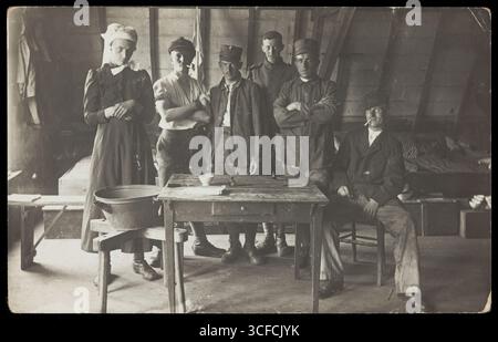 I prigionieri di guerra francesi, uno a trascinamento, si riuniscono intorno a un piccolo tavolo di legno, [tra il 1910 e il 1919?]. Foto Stock