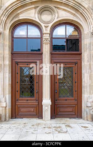 Porte doppie ornate in legno con finestre ad arco. Primo piano di eleganti doppie porte in legno con finestre a reticolo in ferro decorativo e pannelli in vetro ad arco Foto Stock