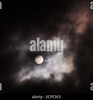 Il sole parzialmente eclissato nelle nuvole Foto Stock