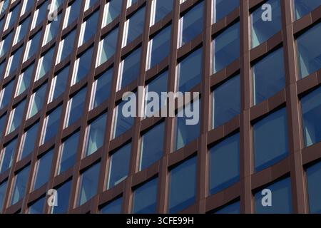 Moderna facciata di un edificio di uffici con cornici marroni e finestre riflettenti in vetro Foto Stock