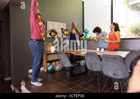 Amici afro-americani appesi alla ghirlanda gialla e alla lettera in sala da pranzo, palloncini Foto Stock