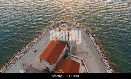 Vista dall'alto della chiesa di nostra Signora della salute a Pirano, con la torre vicino al tramonto e il mare nelle vicinanze. Un'attrazione turistica in Slovenia Foto Stock