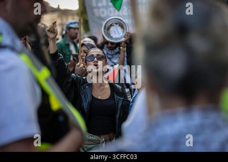 LONDRA, Regno Unito - 22 agosto 2025: Una grande folla di sostenitori palestinesi è contenuta da un cordone di polizia durante una marcia non pianificata fuori dall'ambasciata israeliana. Organizzata dalla campagna di solidarietà per la Palestina, la protesta ha chiesto un cessate il fuoco immediato e un'azione internazionale sull'escalation della situazione a Gaza. Foto Stock