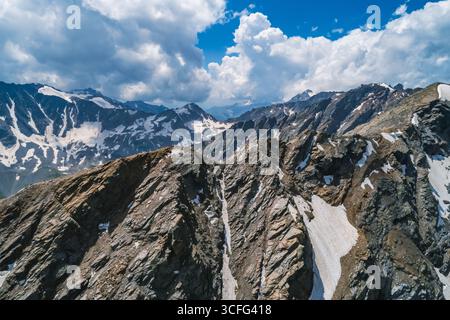 Le cime innevate si innalzano contro un cielo blu pieno di nuvole in una remota regione alpina Foto Stock