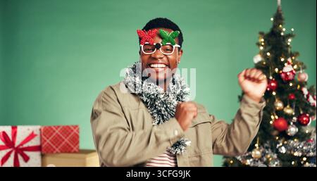 Ritratto, uomo nero e ballo in studio per le vacanze di Natale, feste di Natale e festeggiamenti. Sorridi, persona e musica per prestazioni, ritmo in movimento Foto Stock