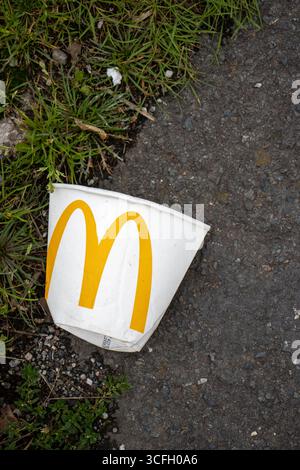 MARSH BARTON, EXETER, DEVON, Regno Unito - 24 SETTEMBRE 2024 rifiuti gettati sulla vergine laterale della strada di marciapiede - tazza di carta monouso McDonalds Foto Stock