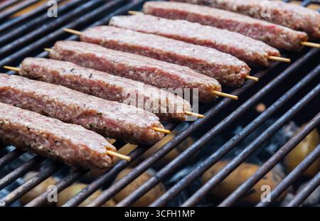 Carne macinata cruda, grigliata su spiedini di legno. Lula Kebab su una griglia. Foto Stock