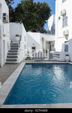 Tranquillo scenario di una piccola piscina privata circondata dalla tradizionale architettura bianca delle Cicladi. Sedie a sdraio, piante in vaso Foto Stock