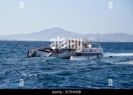 Il relitto di una barca in mare aperto sullo sfondo delle montagne Foto Stock