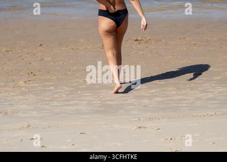 Parte inferiore di una persona non identificata sulla sabbia di una spiaggia durante la forte luce del sole. Attività, direzione, percorso. Brasile Foto Stock