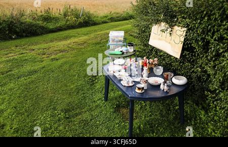 Offerta a Loppis, un mercato delle pulci svedese, solo un tavolo da giardino con qualche merce all'aperto, Vaermland, Svezia Foto Stock